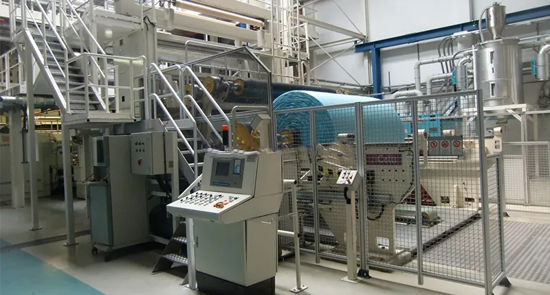 Lamination line with control panel and a roll of blue nonwoven
